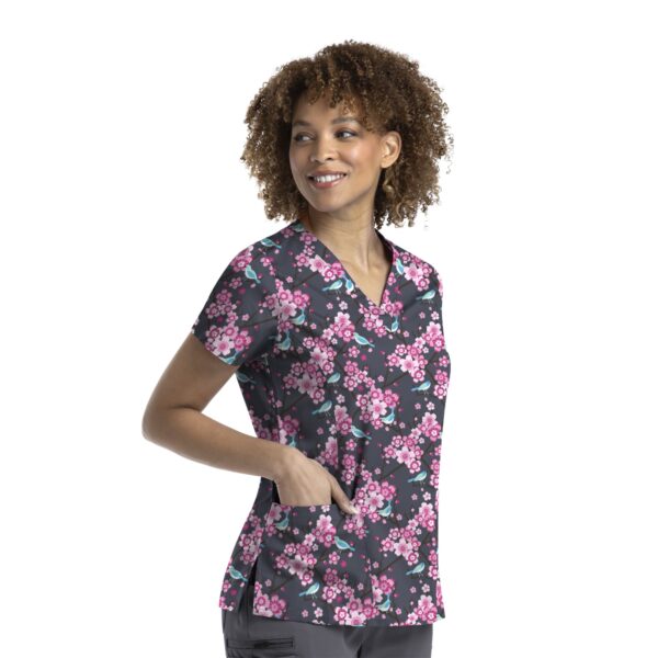 A floral printed curved V-neck top in black with pink and green accents, featuring pockets and a logo.