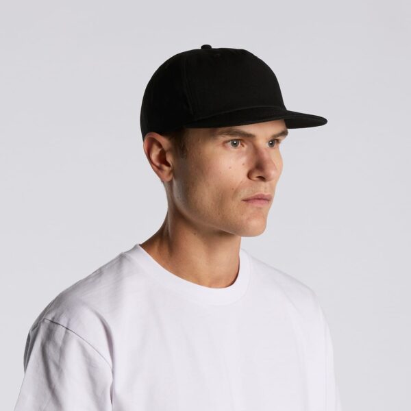 A black cotton cap with a structured design, worn by a male model in a white T-shirt.