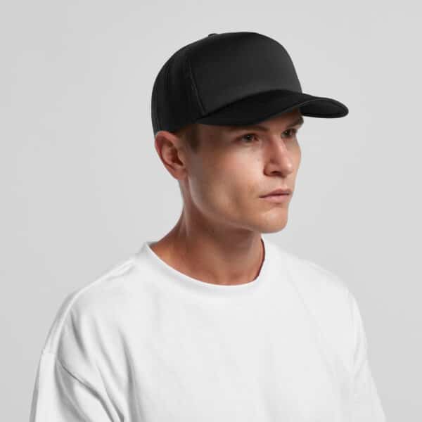 A black trucker cap with a mesh back, worn by a model in a white t-shirt. Features a logo on the front.