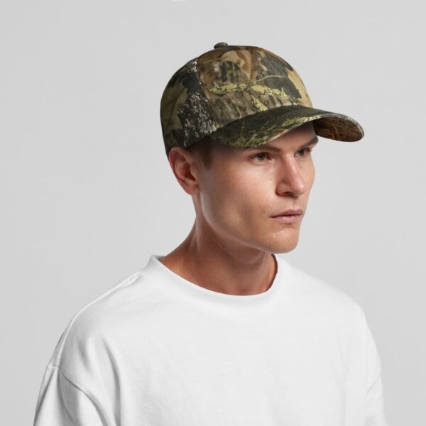 A camo cap in shades of green and brown, worn by a model with short hair, featuring a logo on the front.