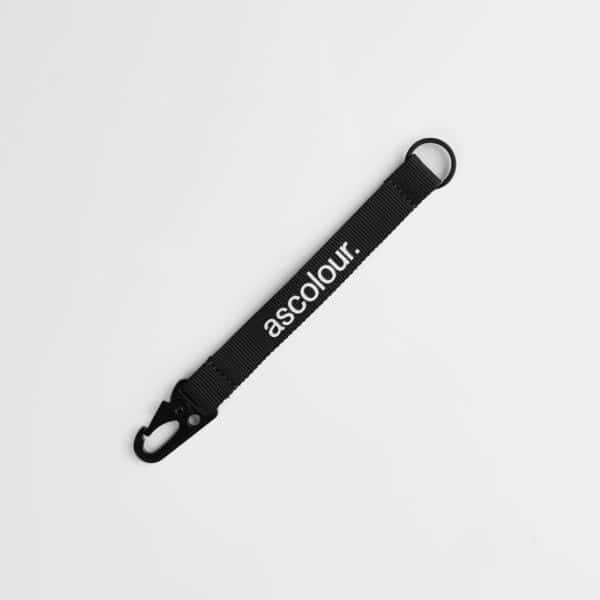 A black keychain made of fabric with a clip and a branding logo.